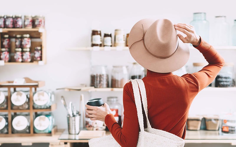 woman looks at store items with a cup of coffee in her hand